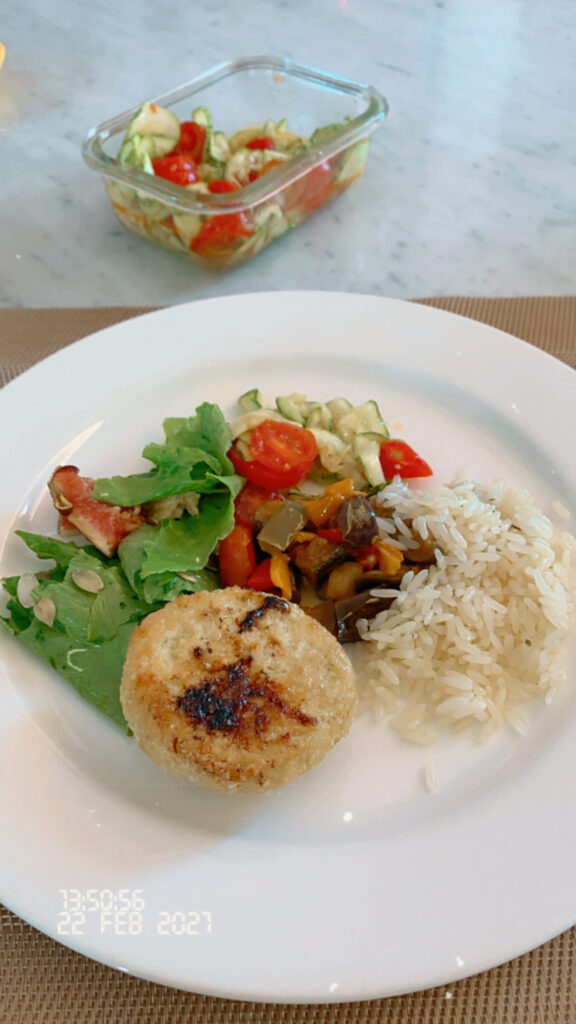 prato com salada, tomates, arroz e hambúrguer de frango